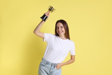 Photo of Happy winner with gold trophy cup on yellow background