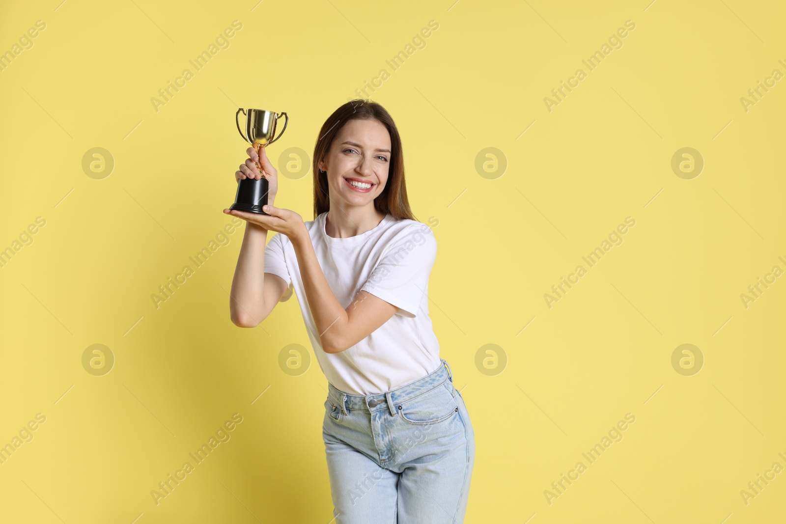 Photo of Happy winner with gold trophy cup on yellow background