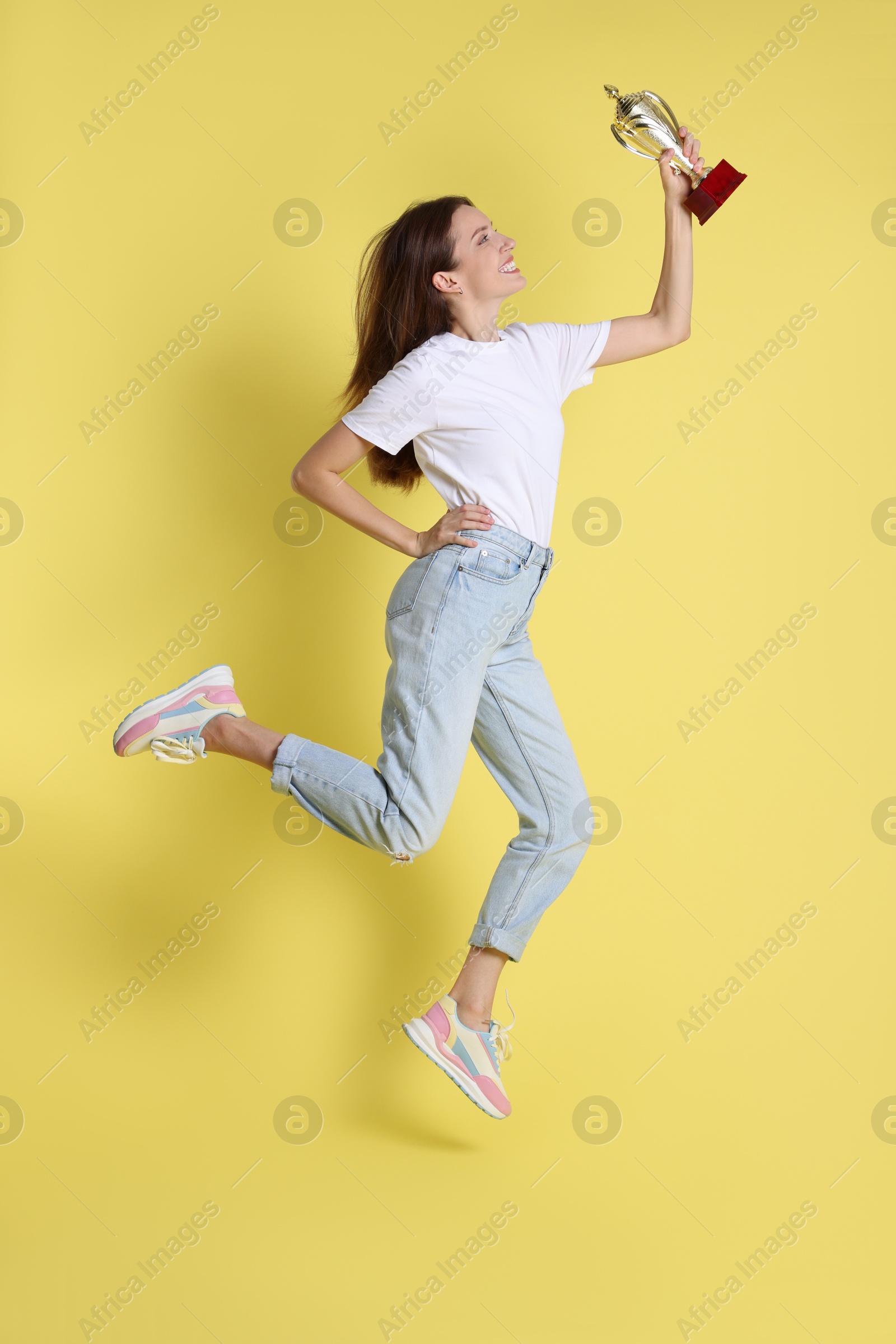 Photo of Happy winner with gold trophy cup on yellow background