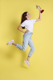 Happy winner with gold trophy cup on yellow background