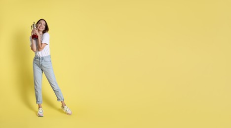 Photo of Happy winner with gold trophy cup on yellow background