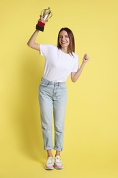 Photo of Happy winner with gold trophy cup on yellow background