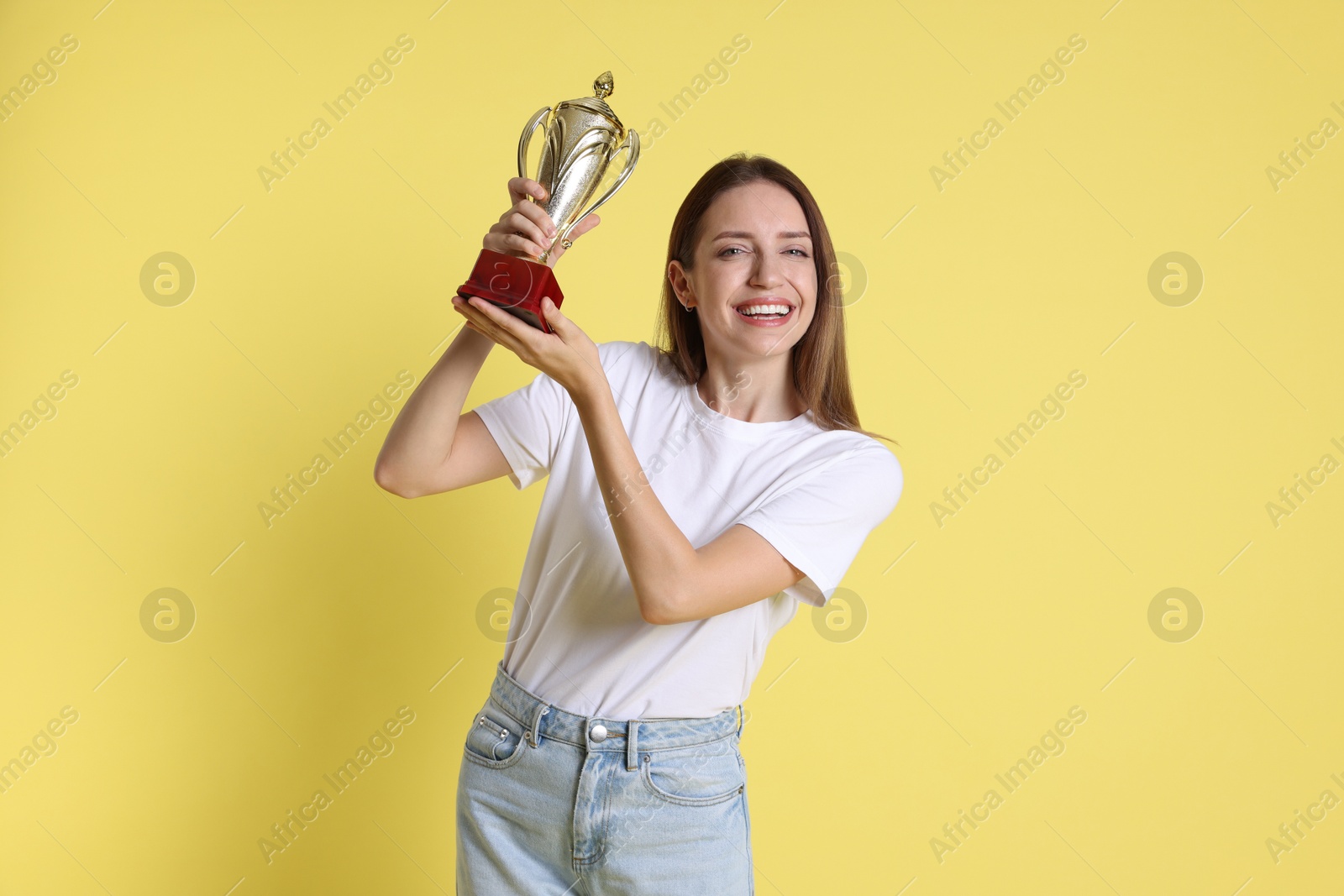 Photo of Happy winner with gold trophy cup on yellow background