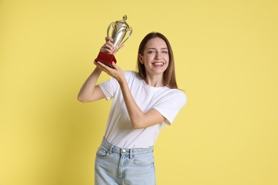 Photo of Happy winner with gold trophy cup on yellow background