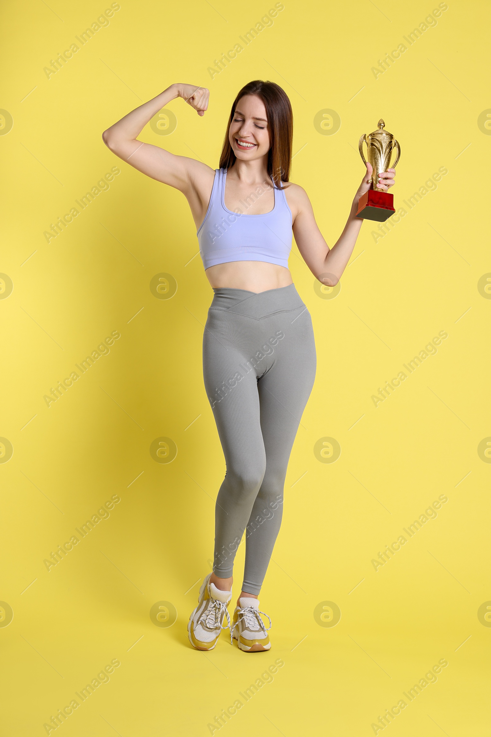 Photo of Happy winner with gold trophy cup on yellow background