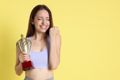 Happy winner with gold trophy cup on yellow background, space for text