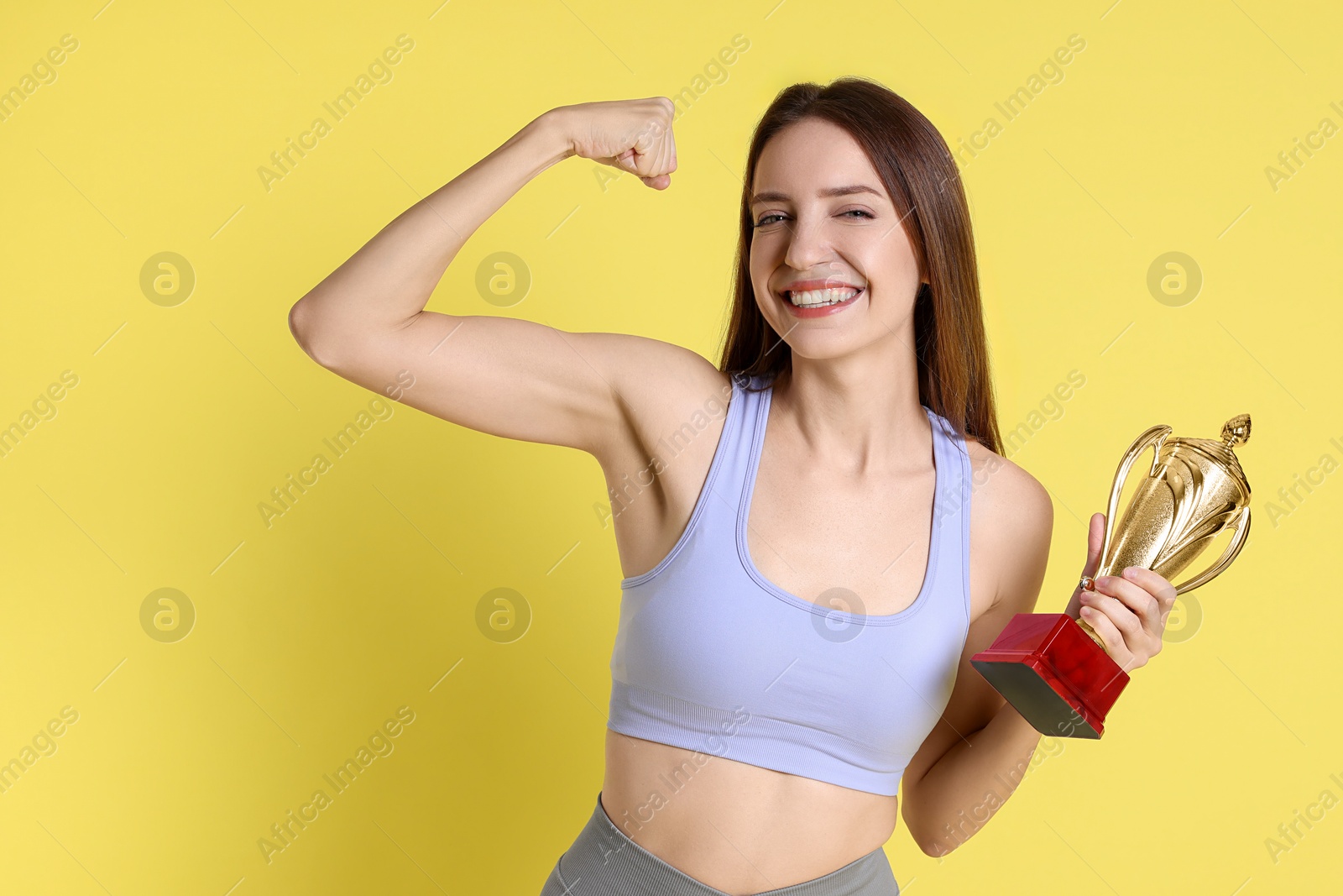 Photo of Happy winner with gold trophy cup on yellow background