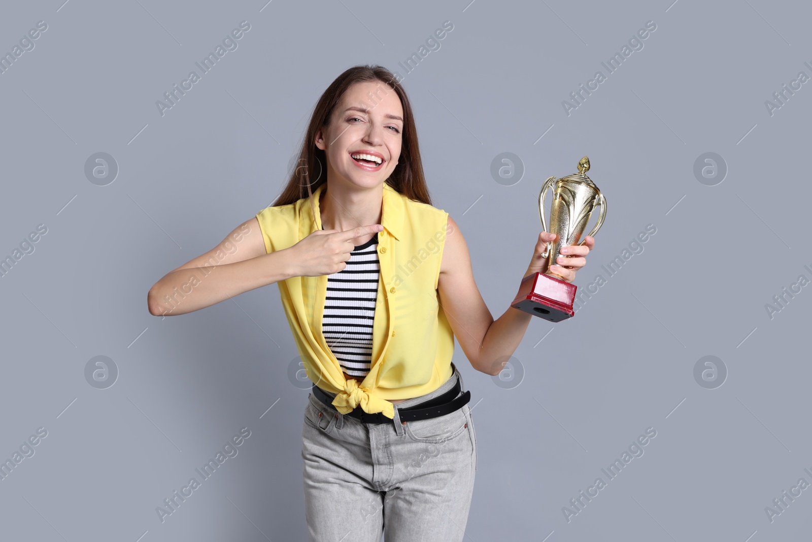 Photo of Happy winner with gold trophy cup on gray background