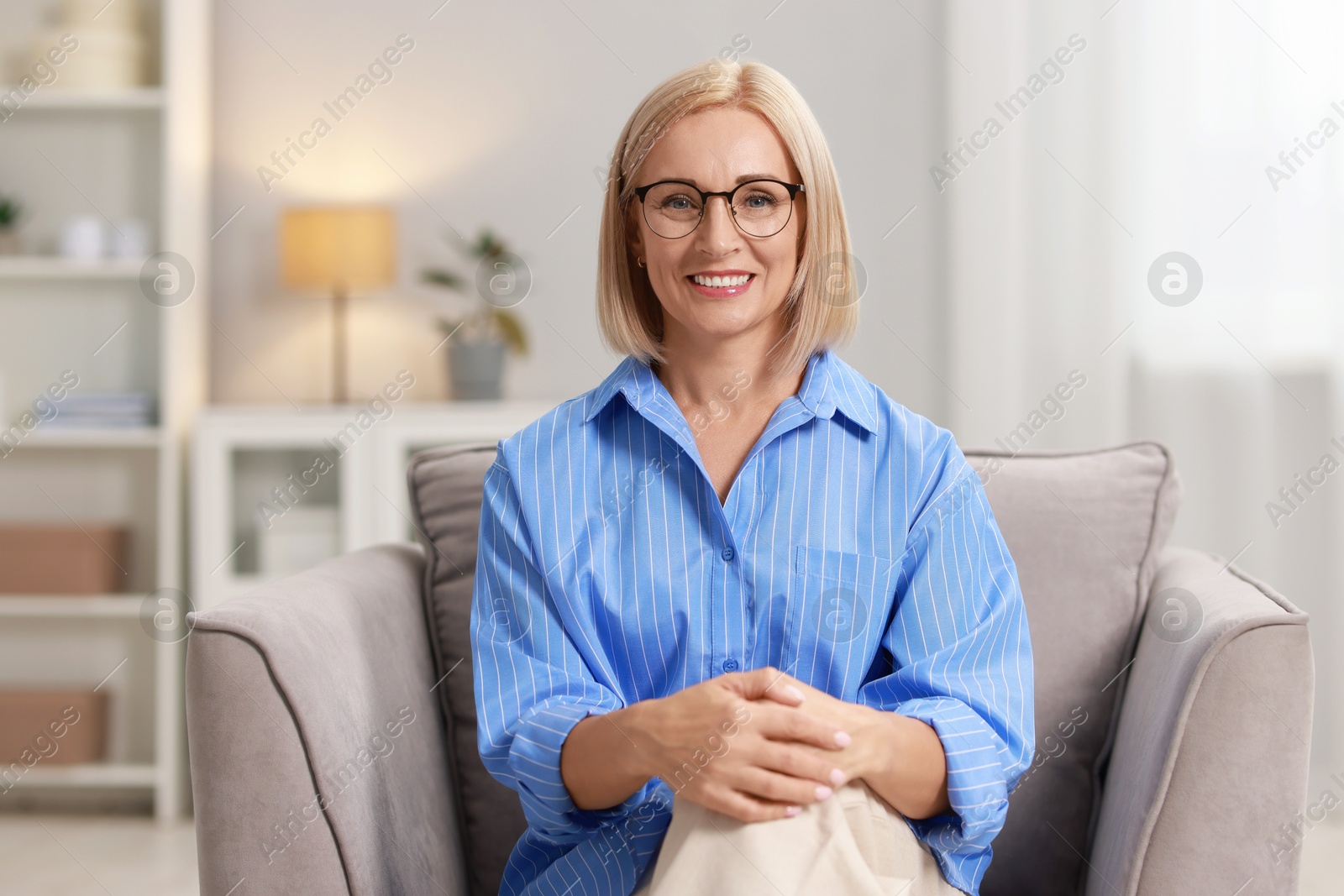 Photo of Portrait of smiling middle aged woman sitting on armchair at home