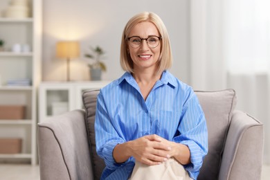 Photo of Portrait of smiling middle aged woman sitting on armchair at home