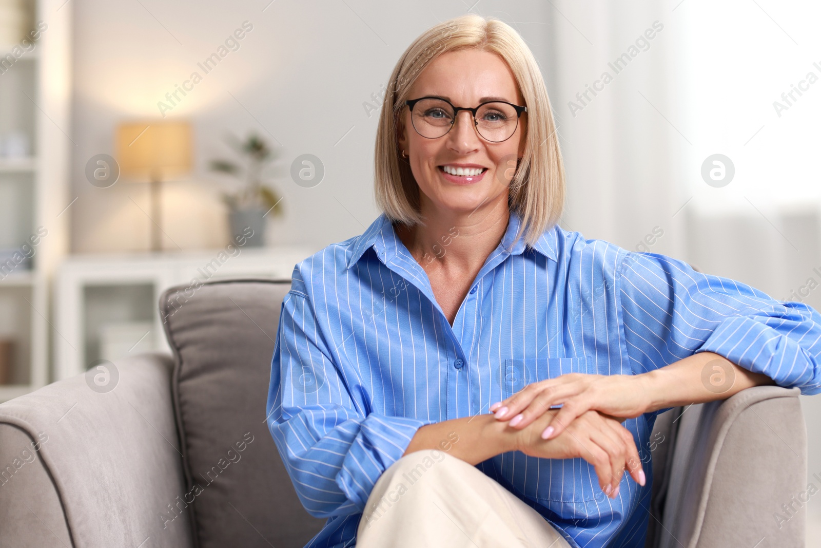 Photo of Portrait of smiling middle aged woman sitting on armchair at home