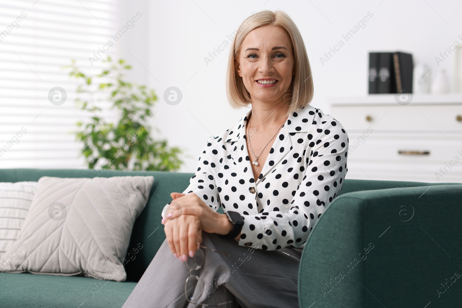 Photo of Portrait of smiling middle aged woman on sofa at home