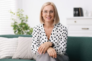 Portrait of smiling middle aged woman on sofa at home