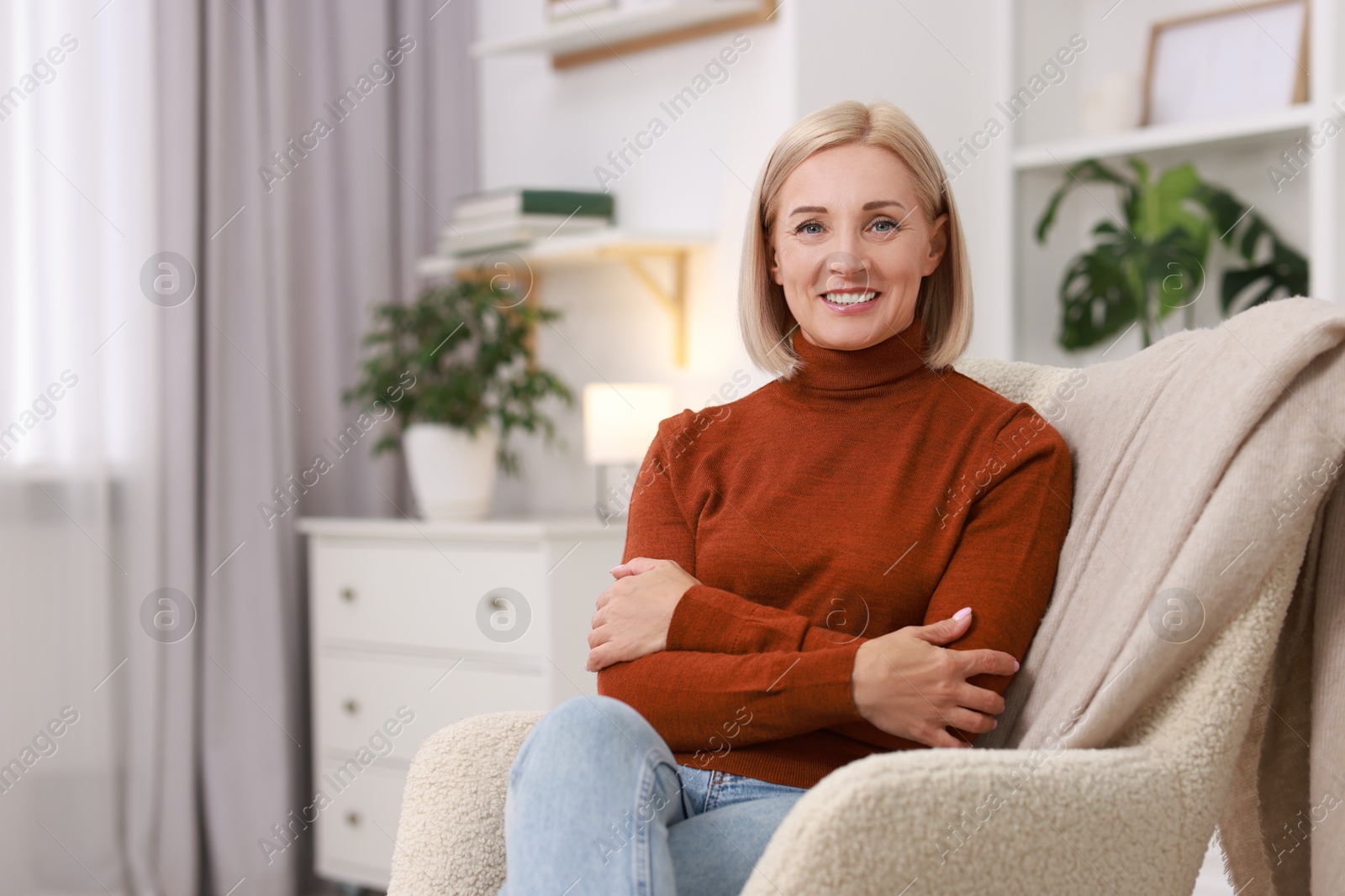 Photo of Portrait of smiling middle aged woman on armchair at home. Space for text