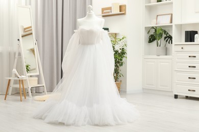 Photo of Beautiful wedding dress on mannequin and shoes in boutique