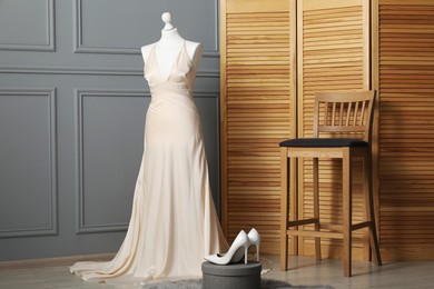 Photo of Beautiful wedding dress on mannequin and shoes in boutique