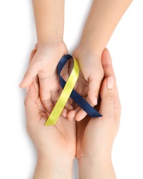 Photo of Woman with child holding yellow and blue ribbon on white background, top view. Down syndrome awareness