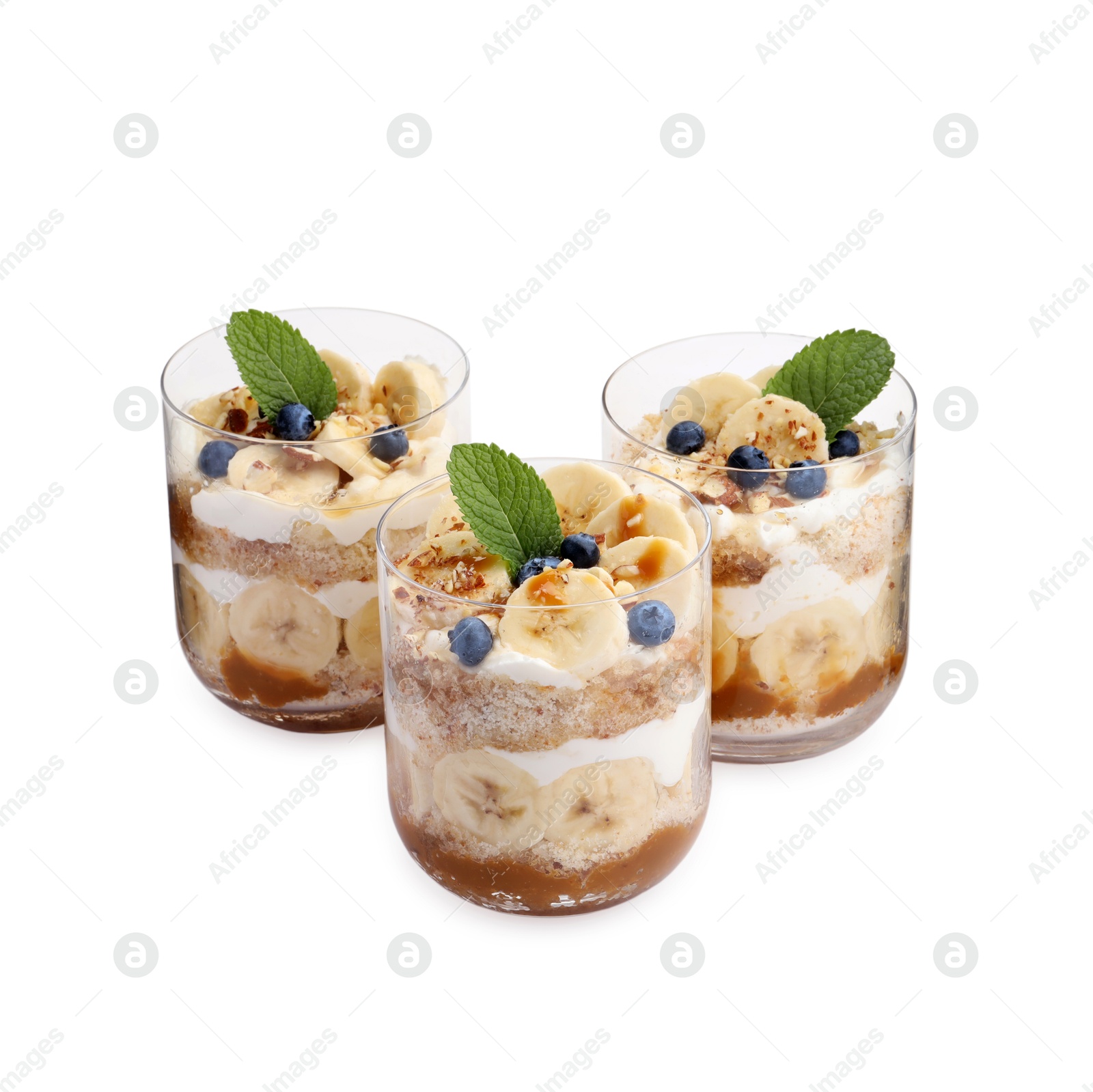 Photo of Tasty trifle dessert. Sponge cake, blueberries, banana and whipped cream in glasses isolated on white