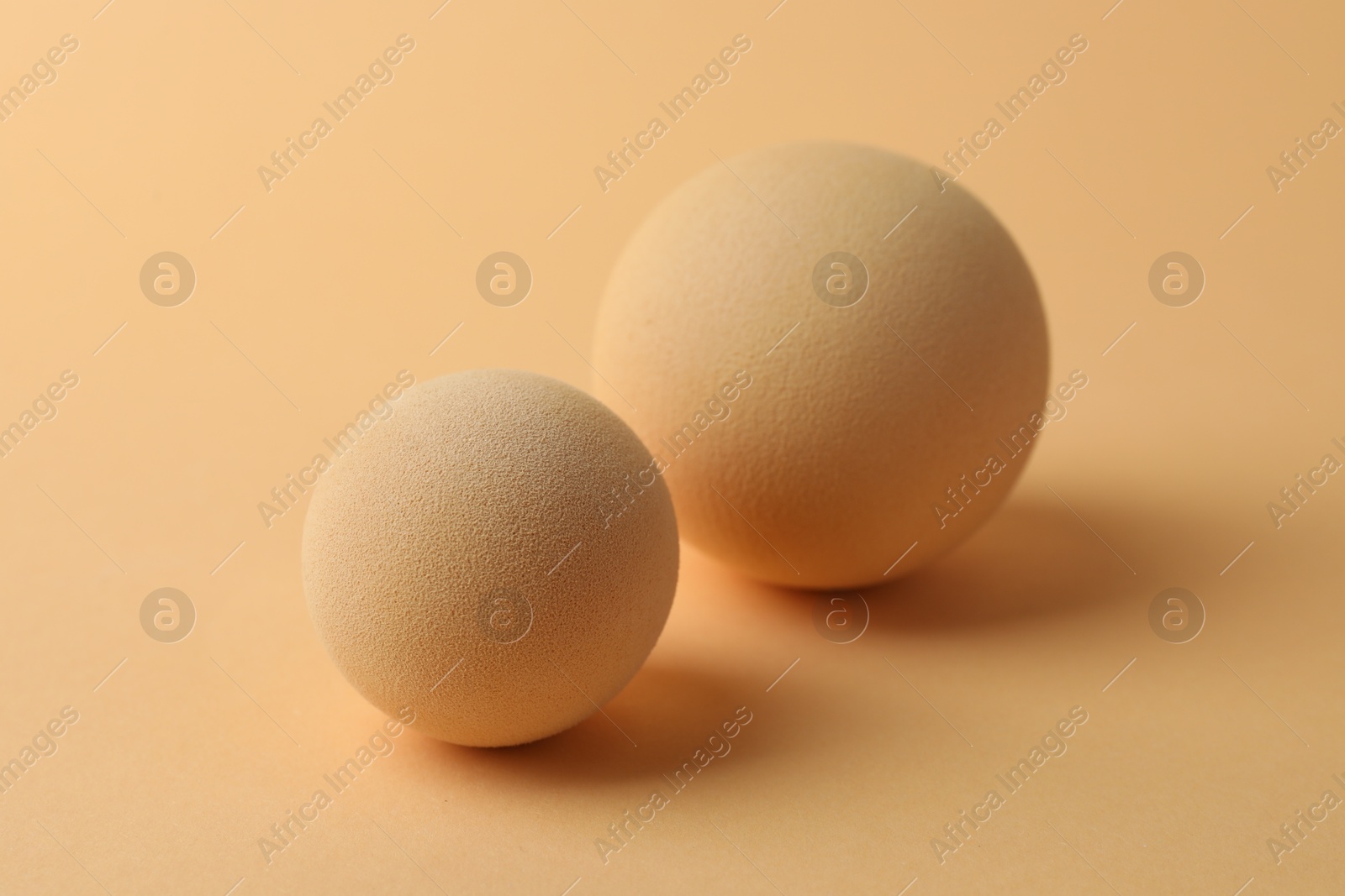 Photo of Two textured balls on beige background, closeup