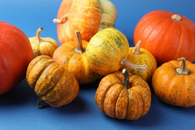 Photo of Group of fresh pumpkins on blue background, closeup