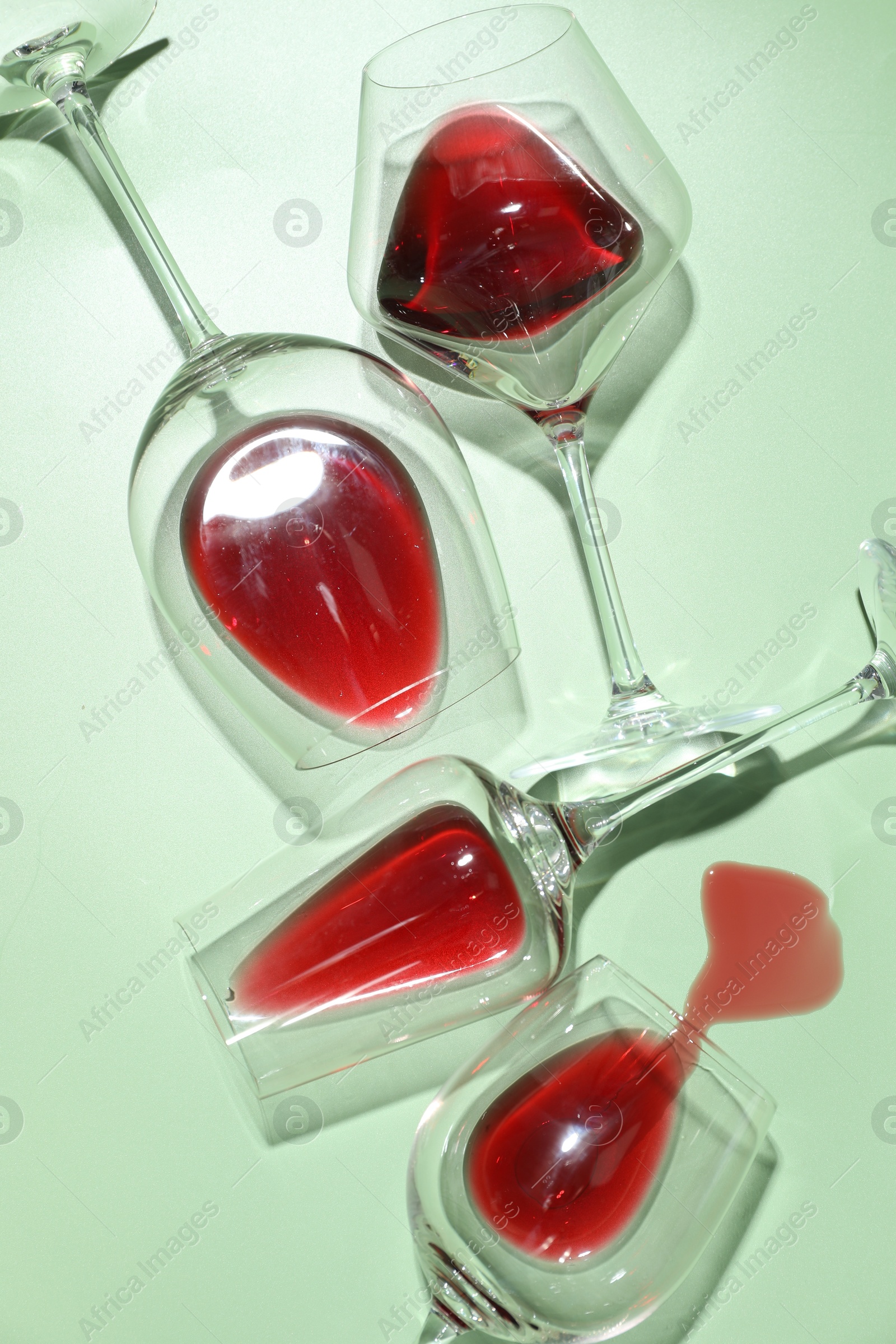 Photo of Glasses of red wine on light green background, flat lay