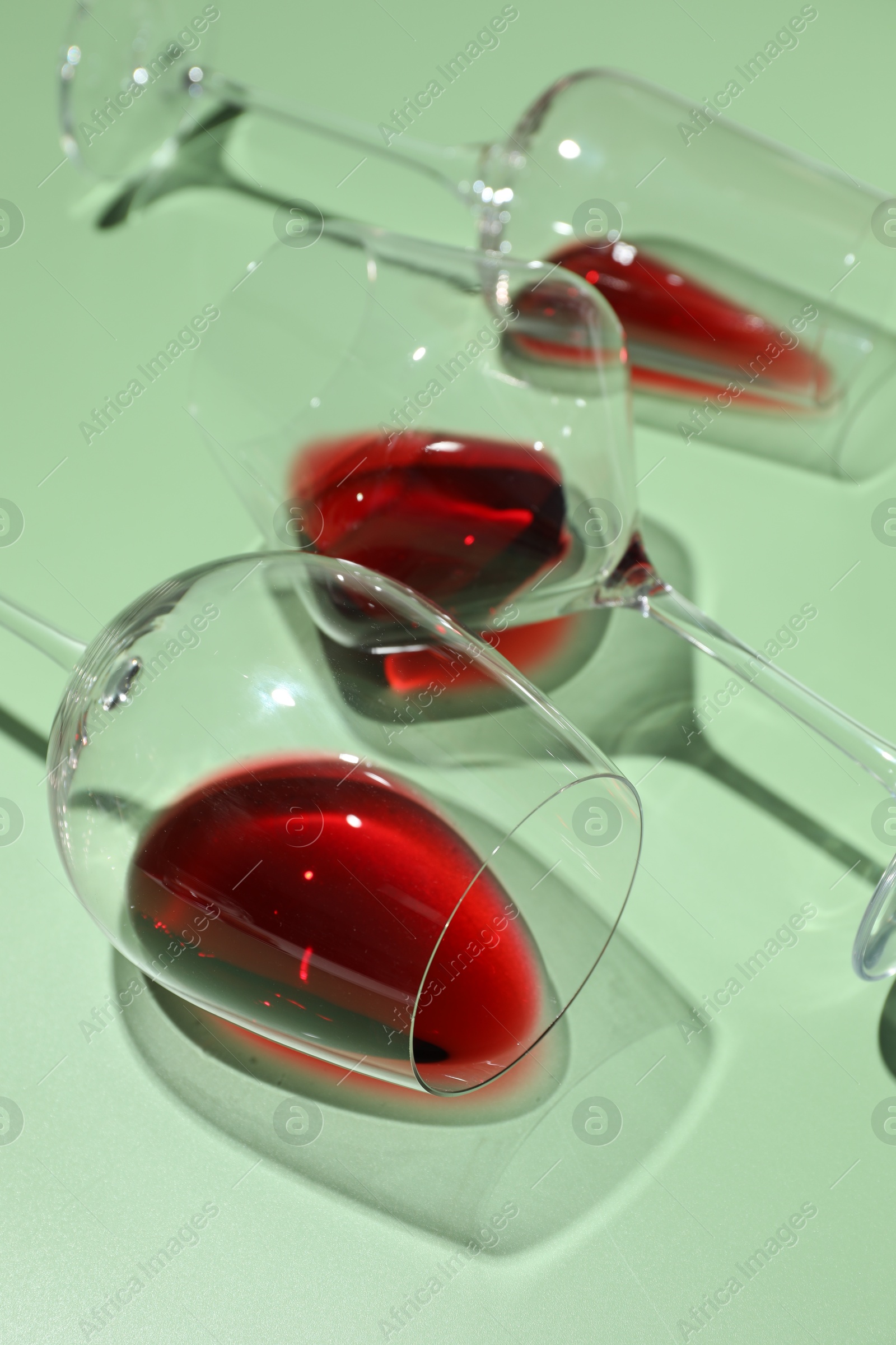 Photo of Glasses of red wine on light green background, closeup