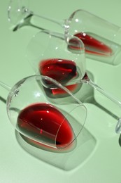 Photo of Glasses of red wine on light green background, closeup