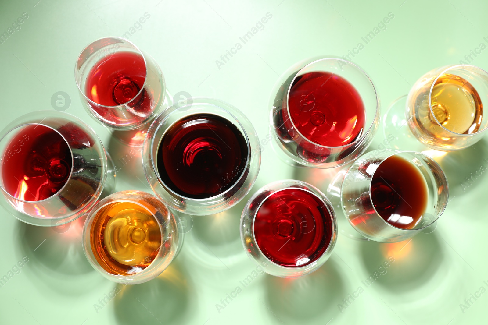 Photo of Glasses of different drinks on light green background, flat lay