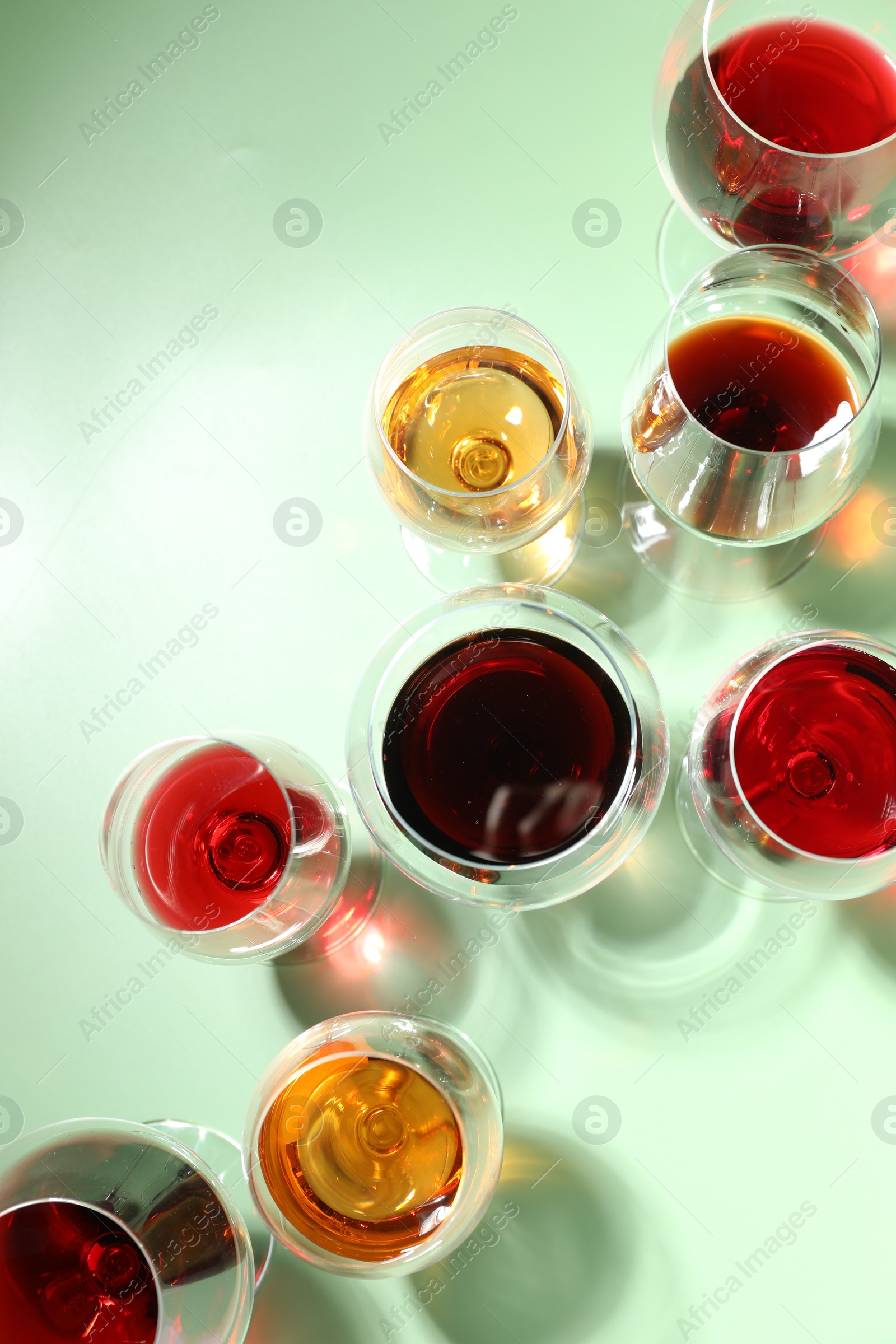 Photo of Glasses of different drinks on light green background, flat lay