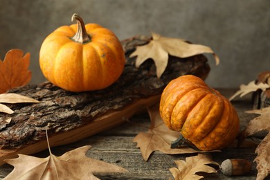 Photo of Fresh pumpkins and dry leaves on wooden table, closeup