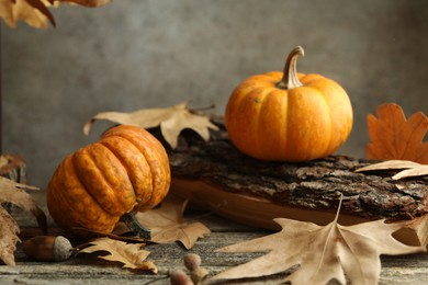 Photo of Fresh pumpkins and dry leaves on wooden table, closeup