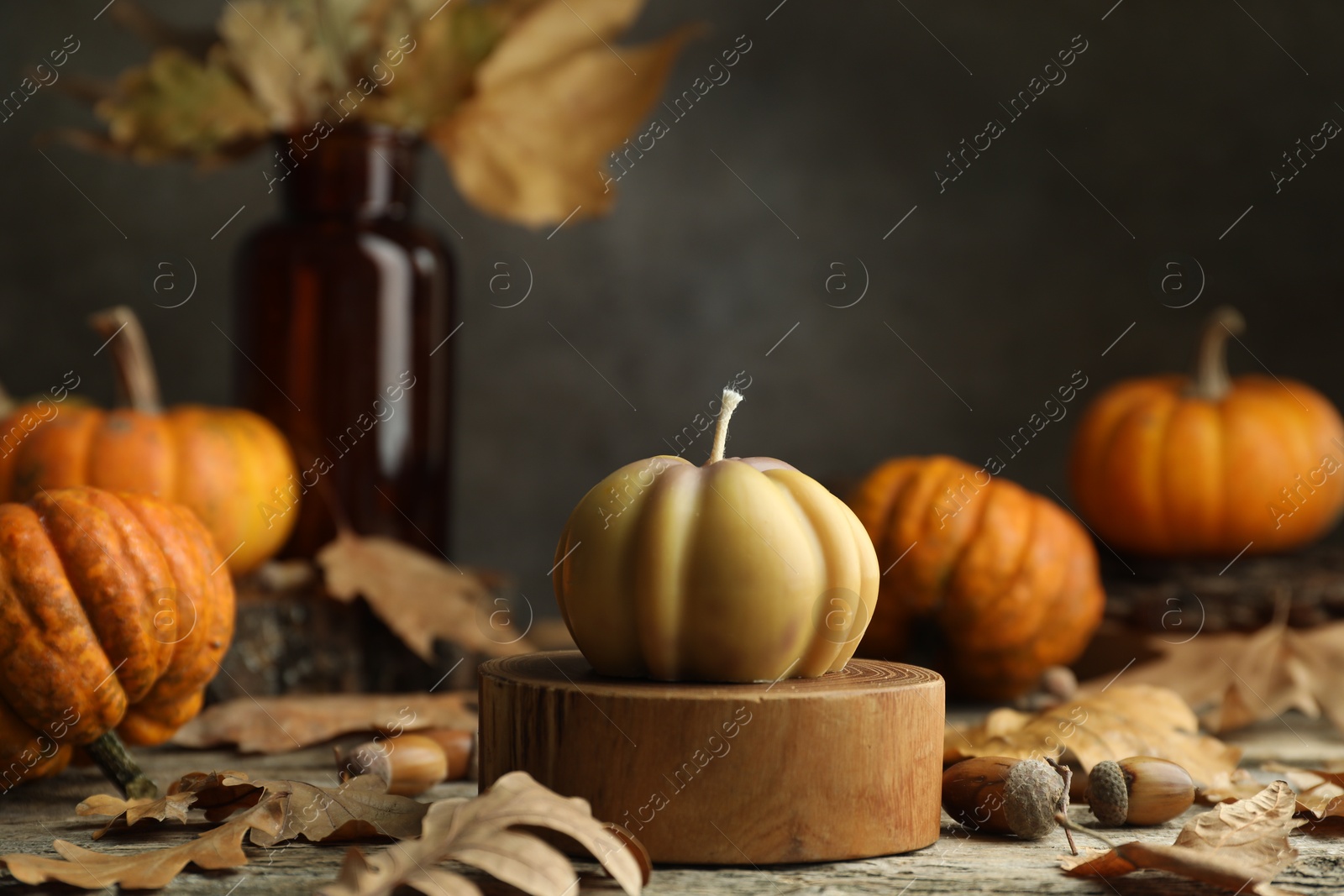 Photo of Autumn atmosphere. Pumpkin shaped candle and dry leaves on wooden table