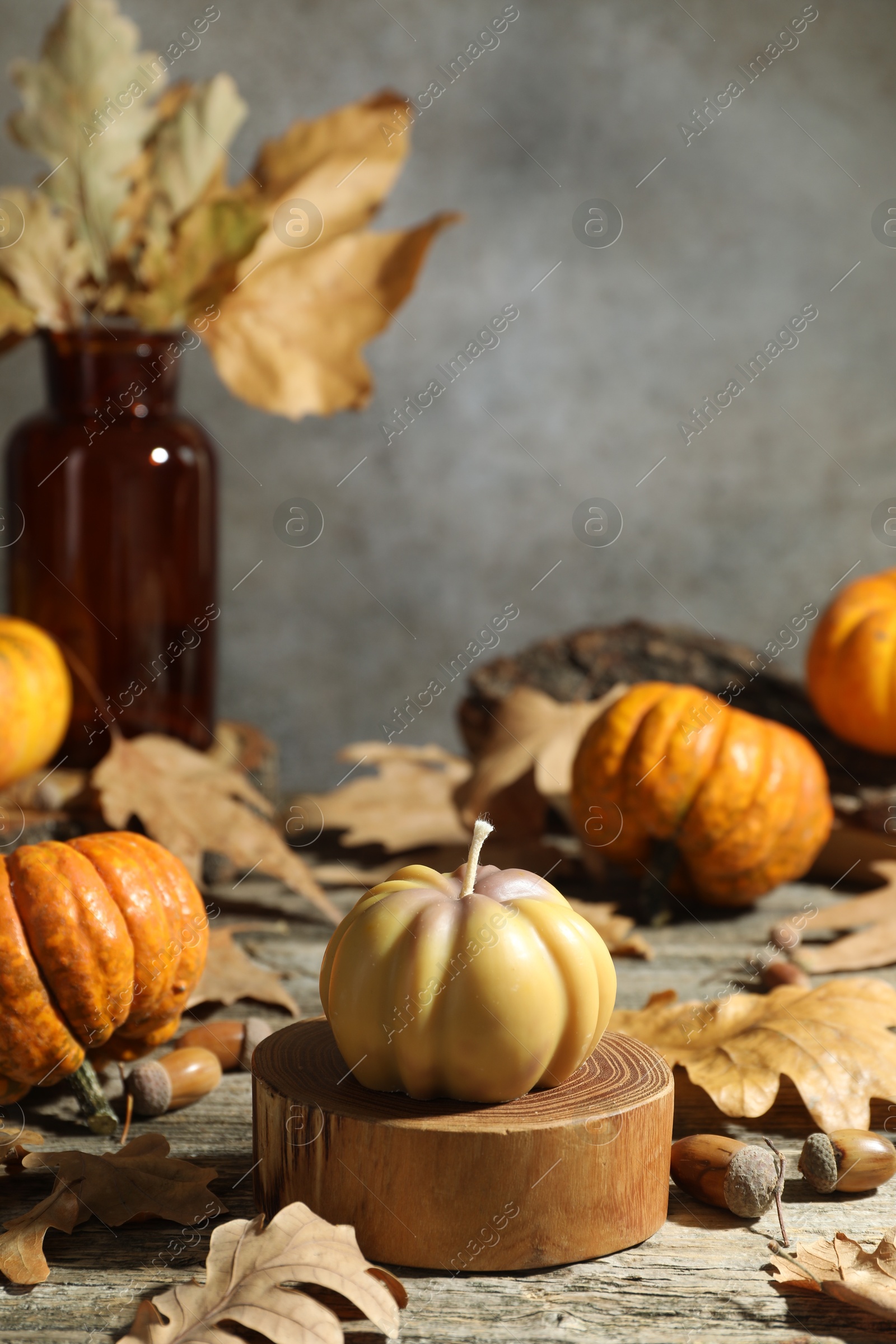 Photo of Autumn atmosphere. Pumpkin shaped candle and dry leaves on wooden table