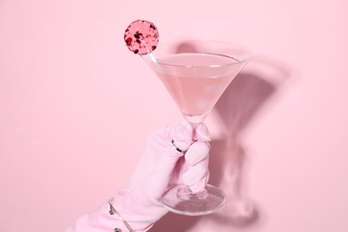 Photo of Woman holding glass of drink on pink background, closeup