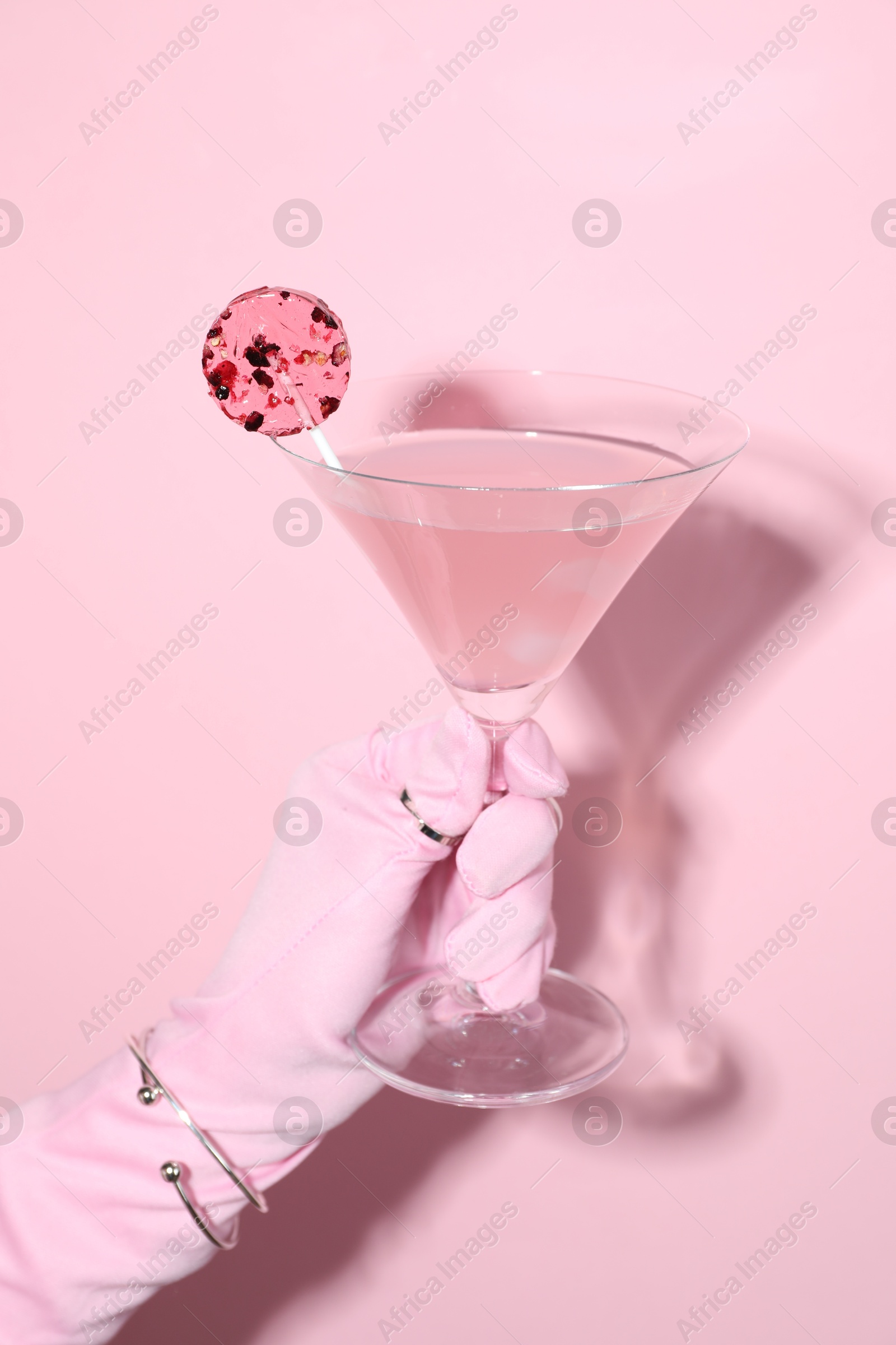 Photo of Woman holding glass of drink on pink background, closeup