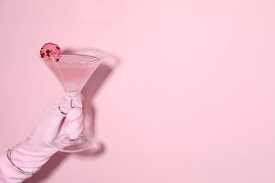 Photo of Woman holding glass of drink on pink background, closeup. Space for text