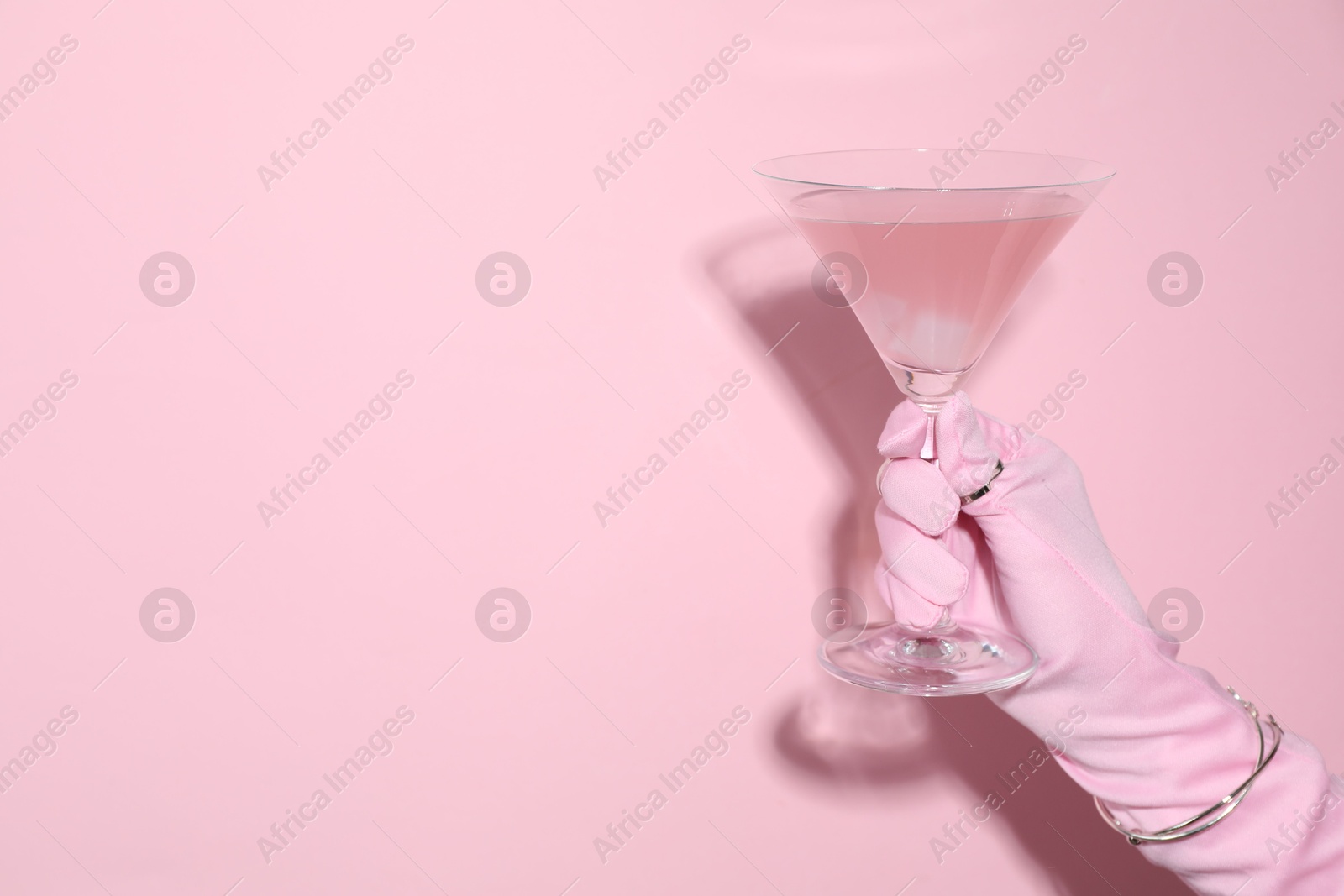 Photo of Woman holding glass of drink on pink background, closeup. Space for text