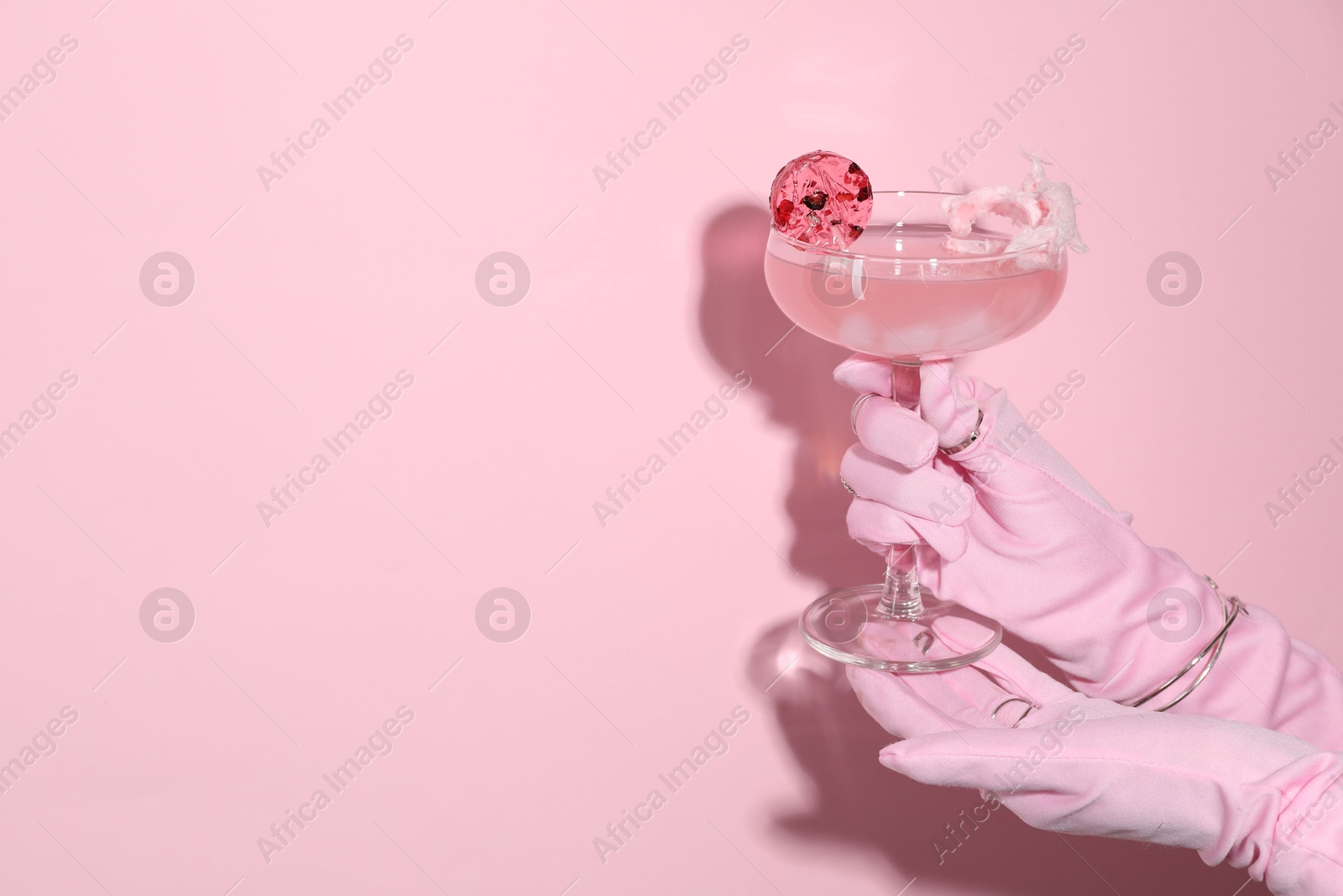 Photo of Woman holding glass of drink on pink background, closeup. Space for text