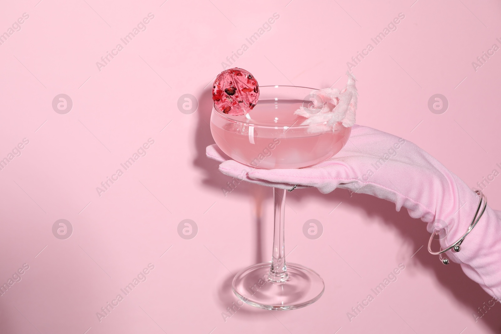 Photo of Woman holding glass of drink on pink background, closeup. Space for text