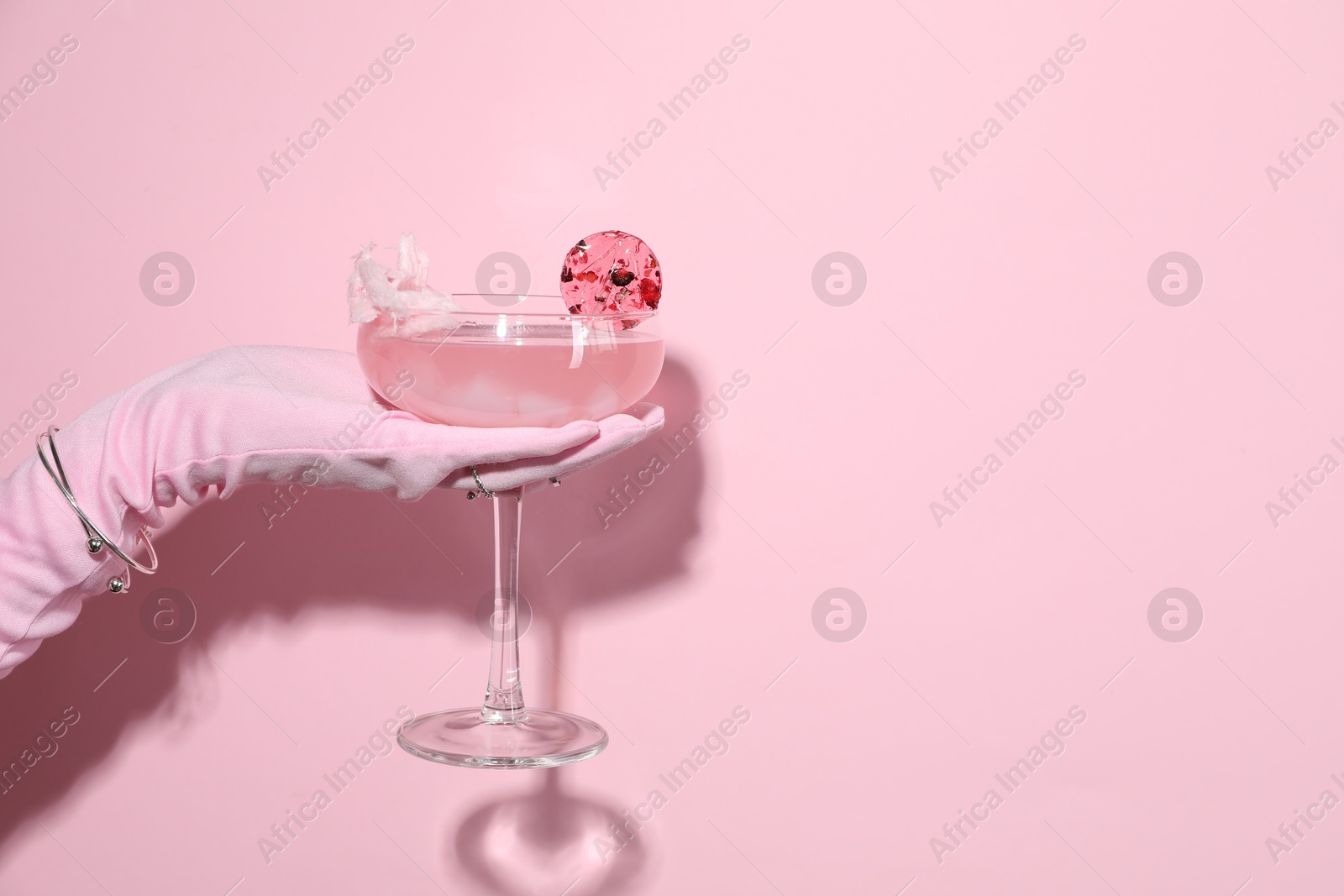 Photo of Woman holding glass of drink on pink background, closeup. Space for text