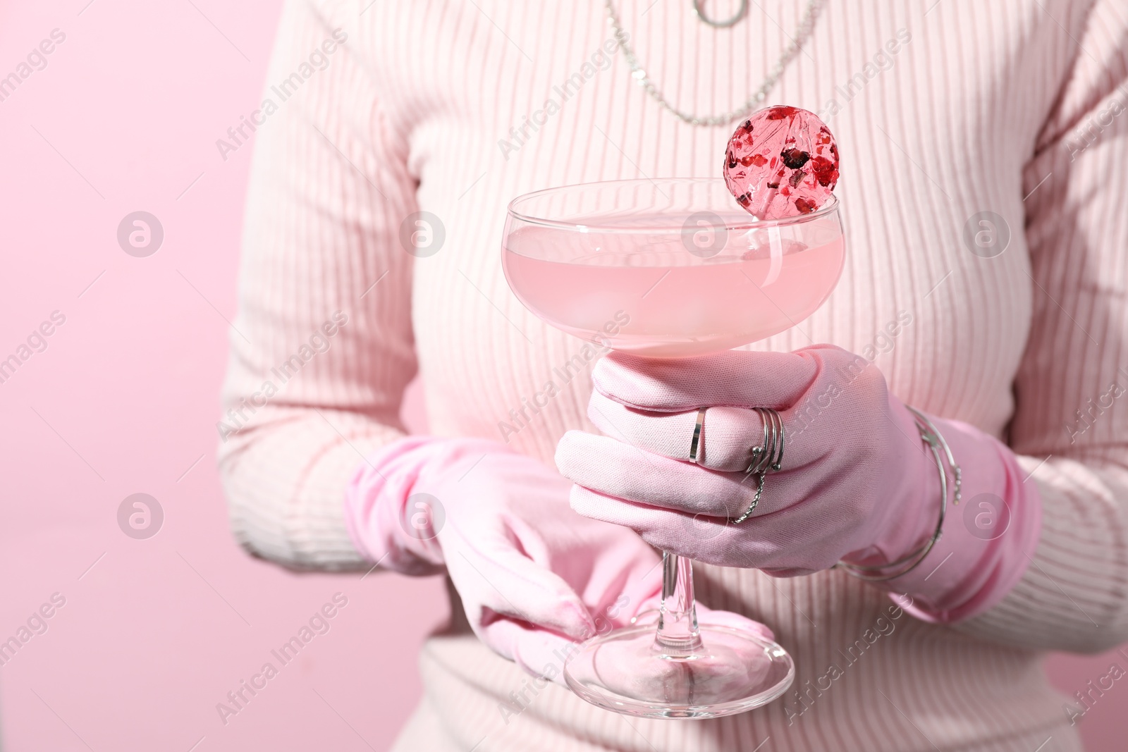 Photo of Woman holding glass of drink on pink background, closeup