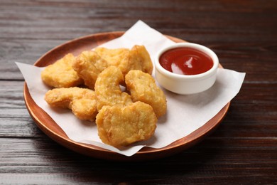 Photo of Delicious chicken nuggets and ketchup on wooden table, closeup