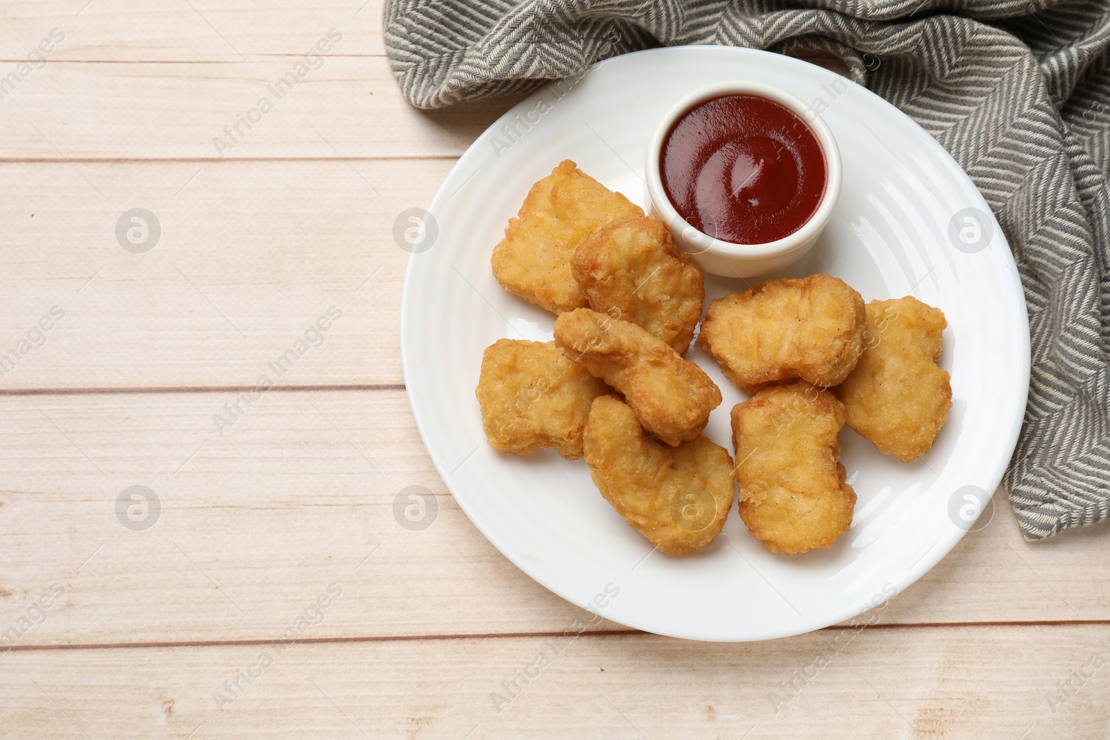 Photo of Delicious chicken nuggets and ketchup on wooden table, top view. Space for text