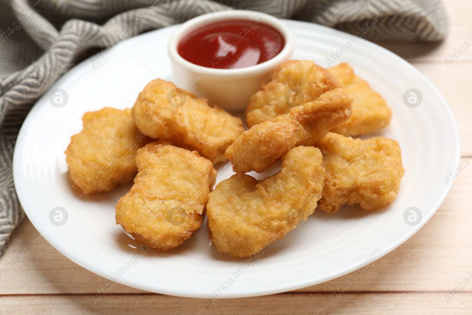 Photo of Delicious chicken nuggets and ketchup on wooden table, closeup