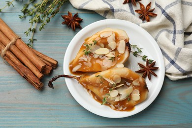 Photo of Delicious pears with caramel sauce, almond flakes and spices on blue wooden table, flat lay