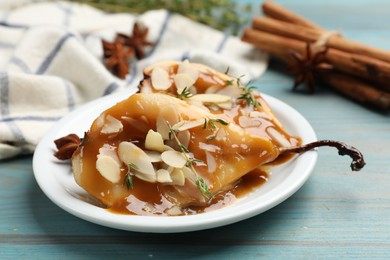 Photo of Delicious pears with caramel sauce, almond flakes and spices on blue wooden table, closeup