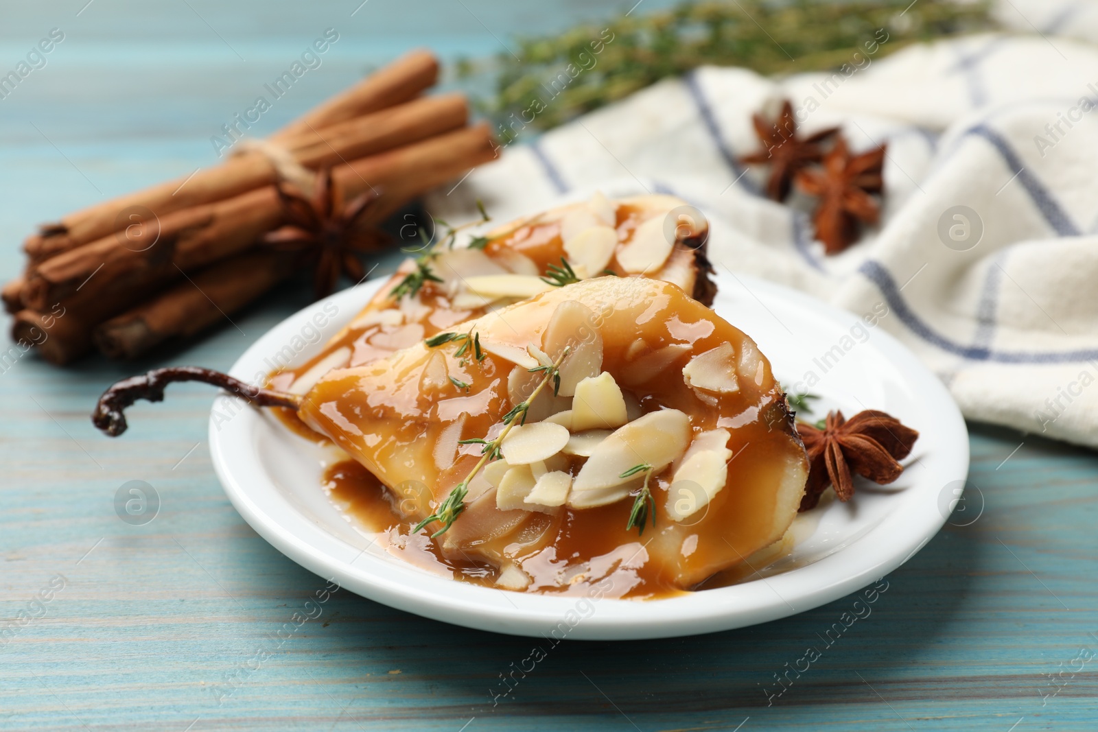 Photo of Delicious pears with caramel sauce, almond flakes and spices on blue wooden table, closeup