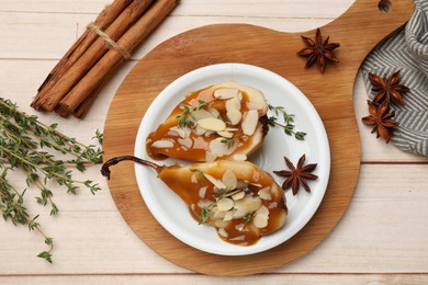 Photo of Delicious pears with caramel sauce, almond flakes and spices on white wooden table, flat lay