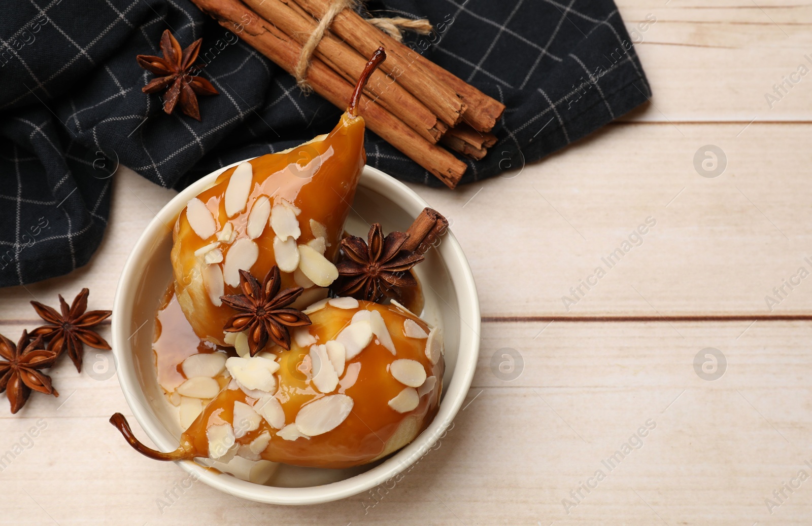 Photo of Delicious pears with caramel sauce, almond flakes and spices on white wooden table, flat lay. Space for text