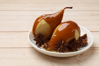 Delicious pears with caramel sauce and spices on white wooden table, closeup